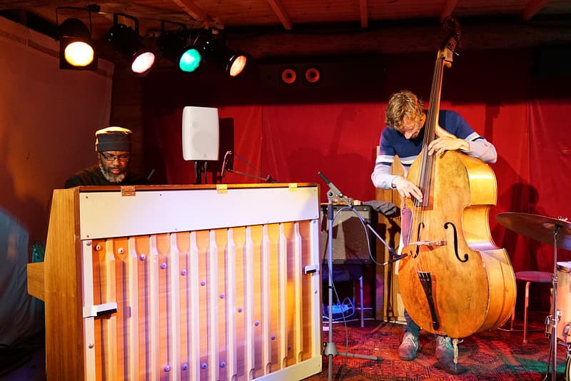 Two musicians performing on stage, one playing a piano and the other playing a double bass.