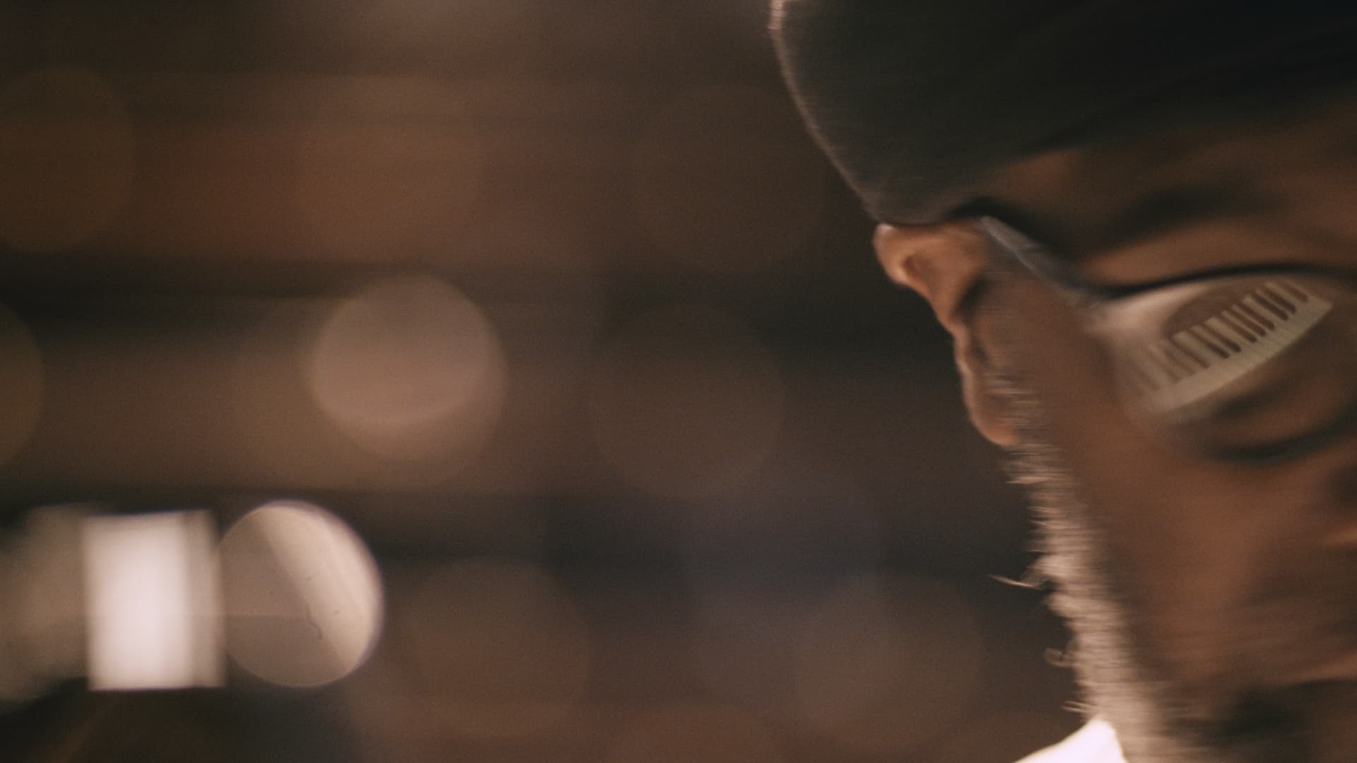 A person with glasses and a hat is partially visible on the right, with a blurred background featuring circular light bokeh.